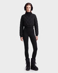 A person stands facing forward against a plain light background, wearing the Rudsak KATYA - 8526531 Black quilted down sweater, complemented by black earmuffs, black leggings, and black winter boots.