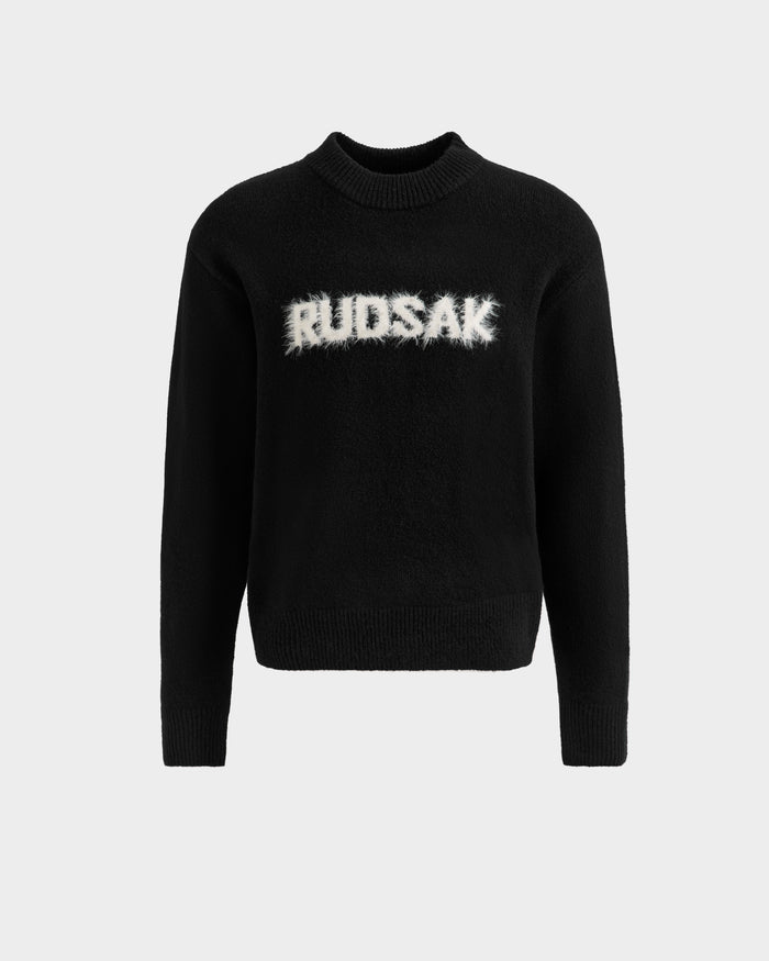 The KINLEY - 9525555 Black M by Rudsak is a black unisex crewneck sweater with ribbed cuffs and hem, featuring the bold RUDSAK logo in large white fuzzy letters—a standout textured knit for any wardrobe.