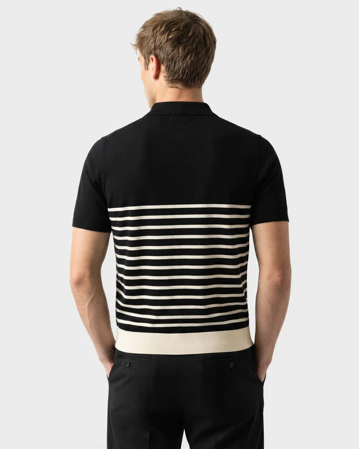 A man faces away, wearing the Rudsak KRIS - 6526005 Black short-sleeve shirt with a contrasting stripe pattern on the lower half and black pants, set against a plain light background.