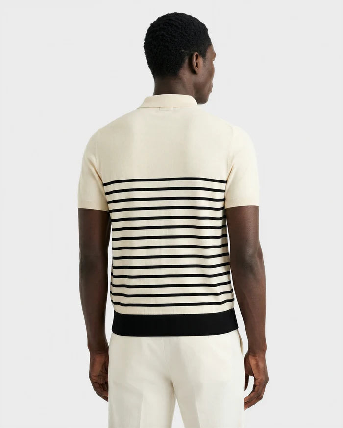 A man faces away, wearing the KRIS - 6526005 Iceland men's summer polo by Rudsak with black contrast stripes on the back, paired with matching cream pants, set against a plain light background.