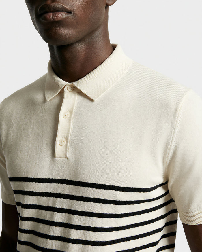 A person wears the KRIS - 6526005 Iceland by Rudsak, a cream fine-gauge knit polo with a collar and black contrast stripes across the chest and sleeves, shown from shoulders to mid-torso against a plain background.