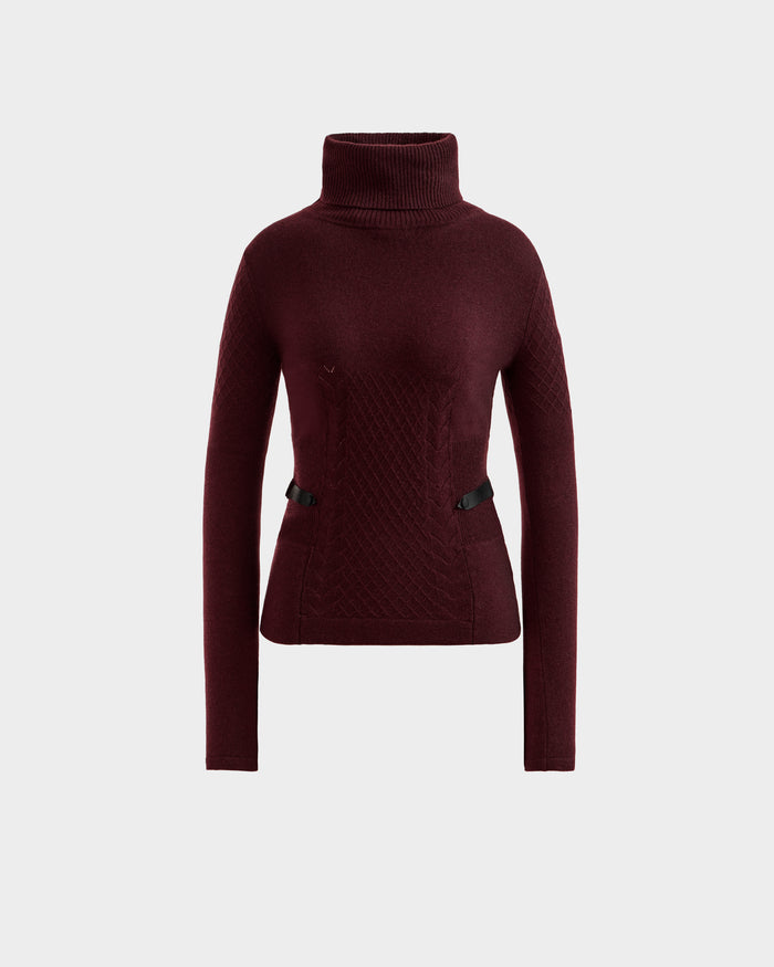 The LAURA - 8524596 Bordeaux by Rudsak is a women’s burgundy knit turtleneck sweater with long sleeves, a fitted waist, textured patterns, and two small black vegan leather waist trims, shown against a white background.