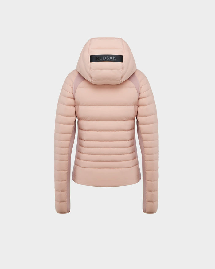 The Rudsak LENA - L124005 is a womens soft pink light down jacket featuring horizontal quilting, a hood, and a black RUDSAK patch. The stylish quilted jacket is shown from the back for a trendy look.