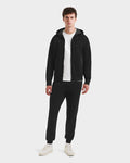 A man faces forward against a plain background, wearing Rudsak’s LEVI - 9525552 Black M unisex zip-up hoodie with vegan leather trims, paired with black joggers, a white t-shirt, and white sneakers.