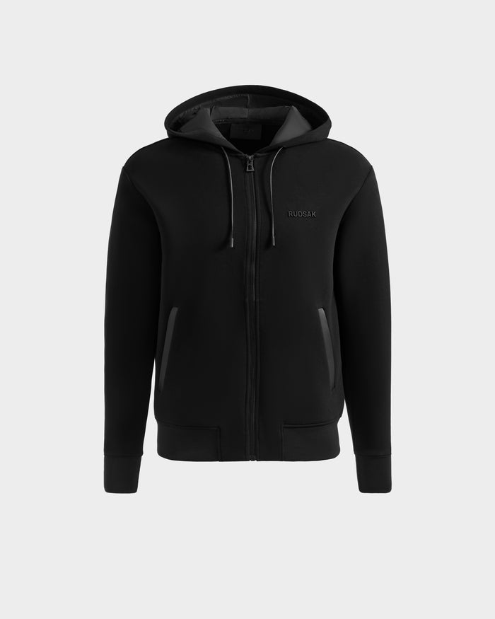 The LEVI - 9525552 Black W by Rudsak is a black unisex cotton-blend zip-up hoodie with a hood, long sleeves, two front pockets, subtle left-chest RUDSAK branding, and vegan leather trims, shown on a plain light gray background.