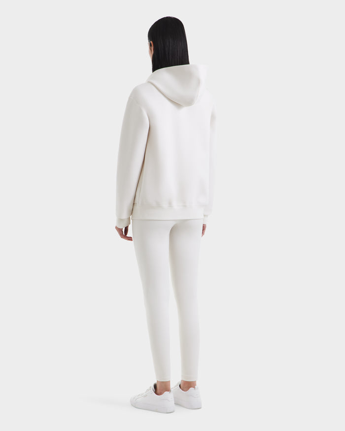 A person with straight dark hair, seen from behind, wears the Rudsak LEVI - 9525552 Vanilla W unisex zip-up hoodie with vegan leather trims, fitted pants, and white sneakers against a plain light background.