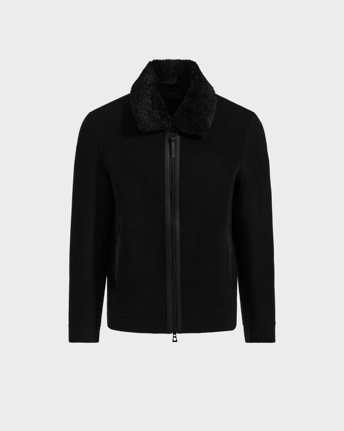 The Rudsak LINCOLN - 6125038 Black men’s coat features a front zipper, side pockets, and a removable soft faux fur collar, shown against a plain light gray background.