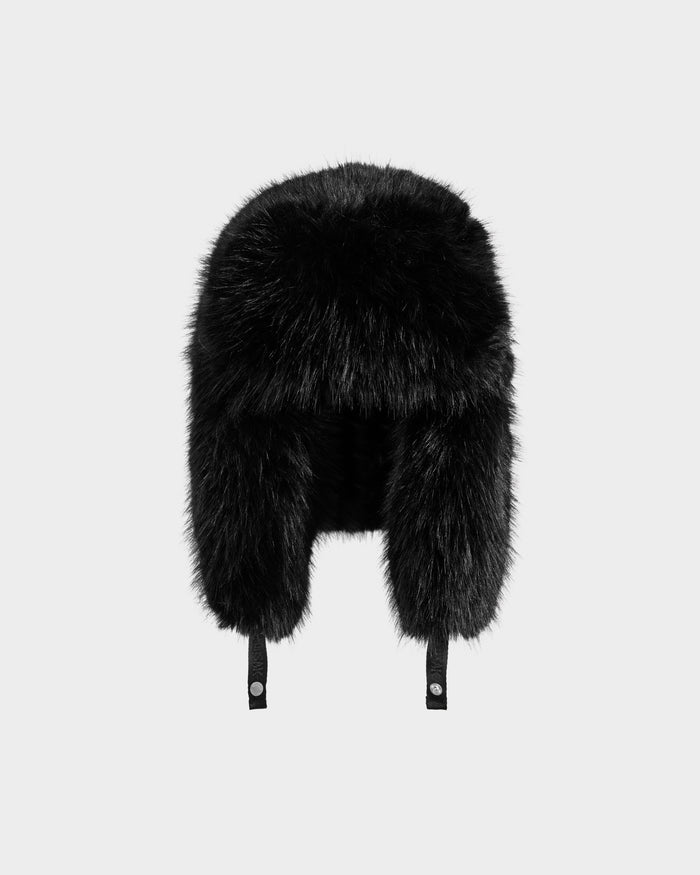 The Rudsak LIRA - 8425024 Black is a women's black faux fur aviator hat with ear flaps and adjustable chin straps, shown against a plain light gray background.