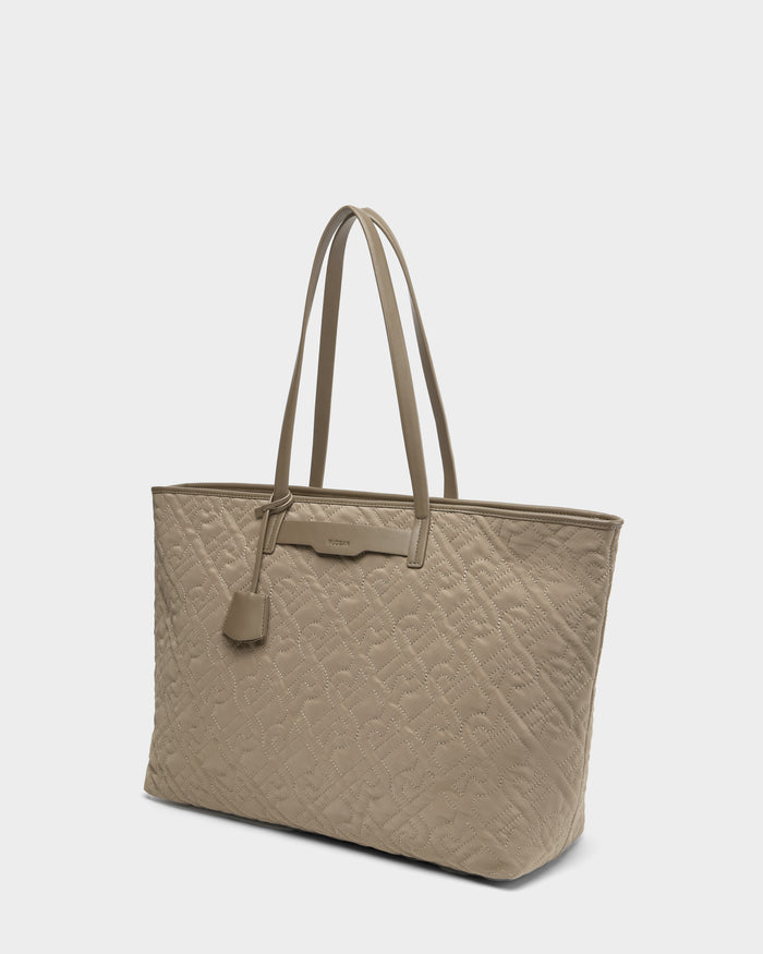 The Rudsak LIVORNO - L325007 Almond tote is a beige quilted monogram carryall with double shoulder straps and a small hanging tag, displayed on a white background—an elegant accessory for any occasion.