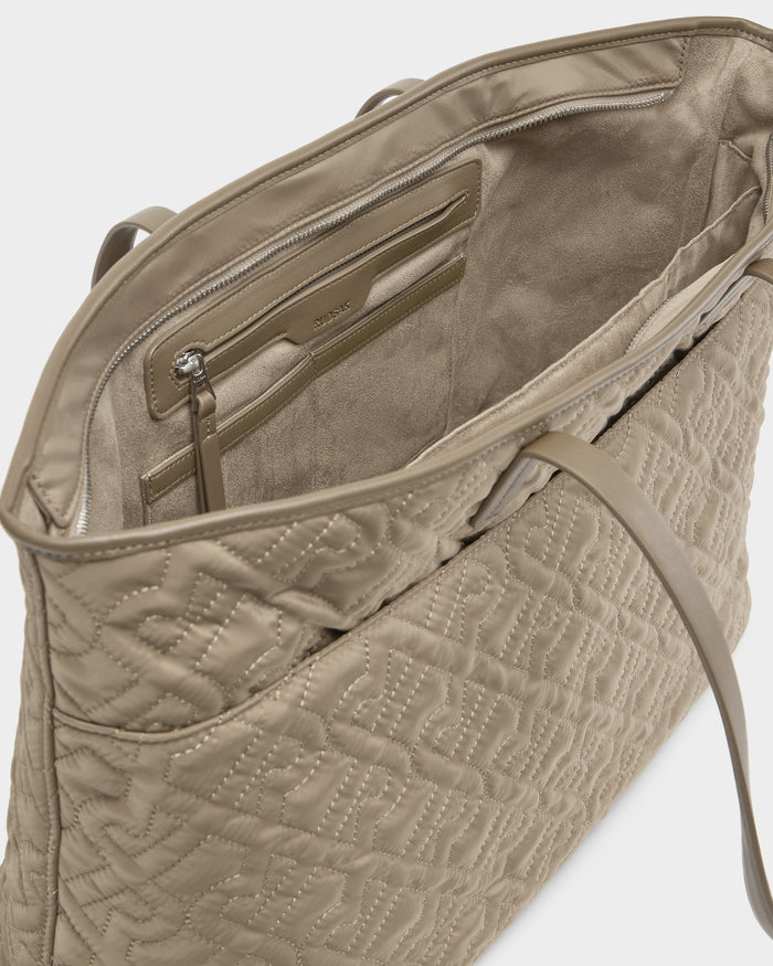 A close-up of the open LIVORNO - L325007 Almond tote by Rudsak shows the beige quilted monogram interior with a zippered pocket, stitched lining, and an attached pouch—your perfect luxury carryall.