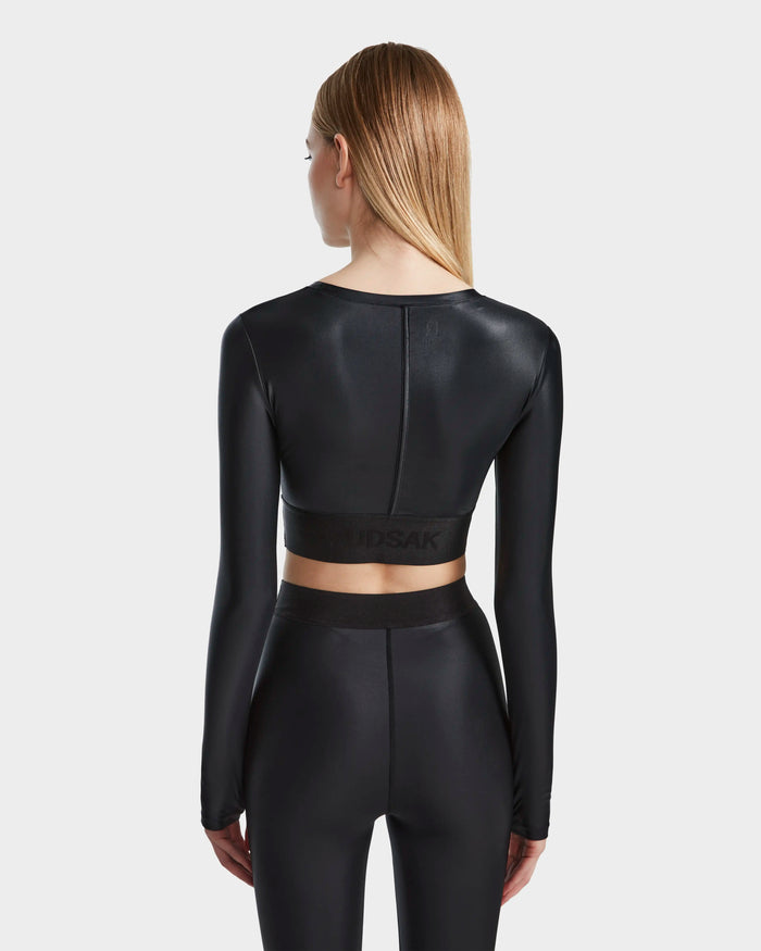 A woman with straight, light brown hair is seen from the back wearing the Rudsak LORA - 8524026 Black women's fitted technical top and matching high-waisted leggings against a plain light background.