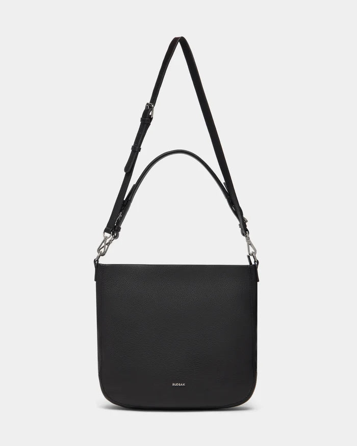 The Rudsak LUCYLE - 8325012 Black is a women’s leather hobo bag with silver hardware, a wide adjustable strap, top handle, subtle logo near the bottom, and a medium-sized minimalist design.