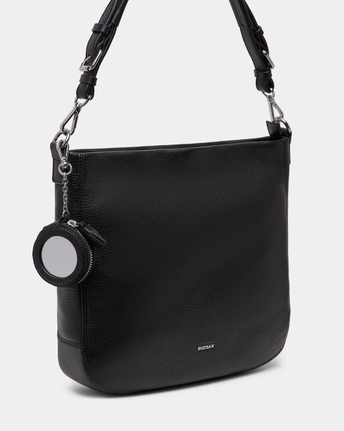 The LUCYLE - 8325012 Black by Rudsak is a medium-sized womens leather hobo bag with silver hardware, a detachable strap, and a small round zippered coin pouch on the handle. Rudsak is printed near the bottom for a signature touch.