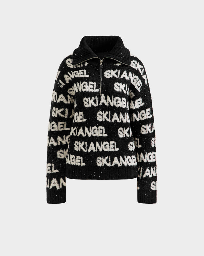 The LYDIA - 8525687 Black by Rudsak is a black and white fuzzy winter knit women’s sweater with a zip-up collar and bold SKIANGEL print, offering cozy après-ski style. Displayed on a plain white background.
