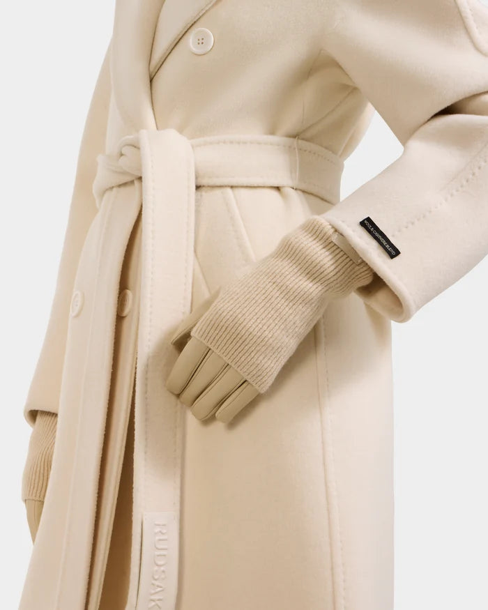 A mannequin models the Rudsak MARINE - 8424516 Vanilla coat, a cream wool piece with ribbed knit cuffs, front buttons, and a sleeve tag, paired with beige women's leather gloves—an ideal fall fashion accessory.
