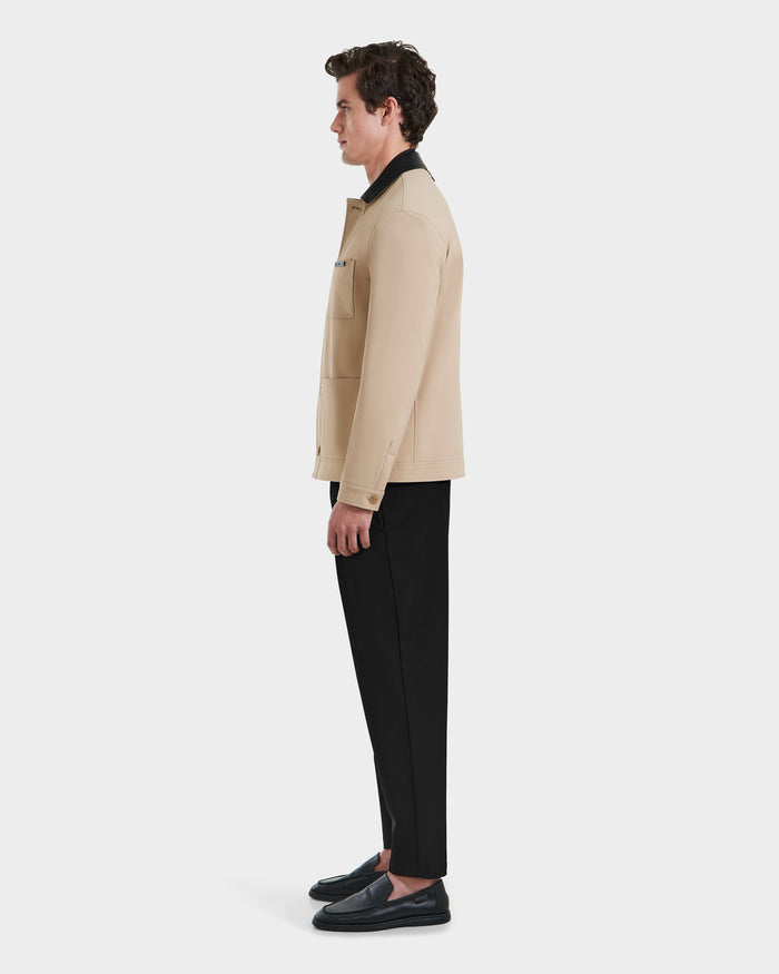 A man in profile faces left, wearing the Rudsak MATTHEW - 6125004 Almond blazer-style shirt jacket, paired with black pants and shoes, set against a plain white background.
