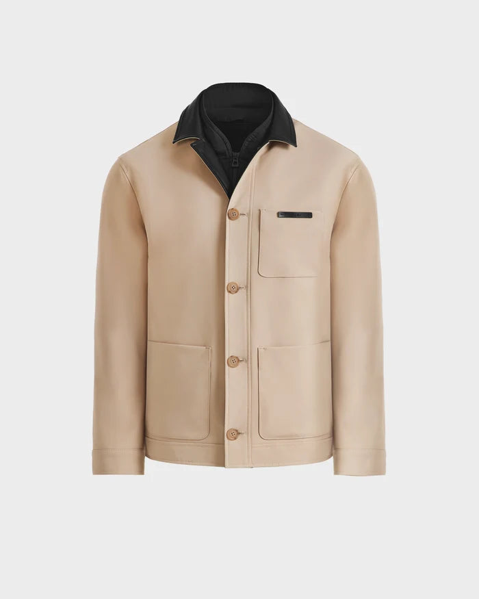 The Rudsak MATTHEW - 6125004 Almond is a beige tailored blazer-style shirt jacket with a black inner collar, three front pockets, and tan buttons, made from technical fabric and shown against a plain white background.