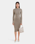 A woman faces forward in the Rudsak MAYLIN - 8523504 Cement Pattern dress, styled with white pointed shoes and a light beige handbag. She has straight brown hair, a neutral expression, and stands against a plain white background.