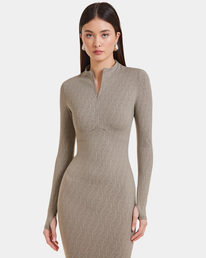 A woman with long dark hair wears the MAYLIN - 8523504 Cement Pattern dress by Rudsak, a fitted taupe womens dress featuring a subtle geometric design and front zipper. She stands against a plain white background, facing forward.
