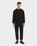 A young man faces forward against a white background, wearing the Rudsak MILOS - 6525646 Black men’s premium cotton blend crewneck sweatshirt with matching black pants and sneakers.