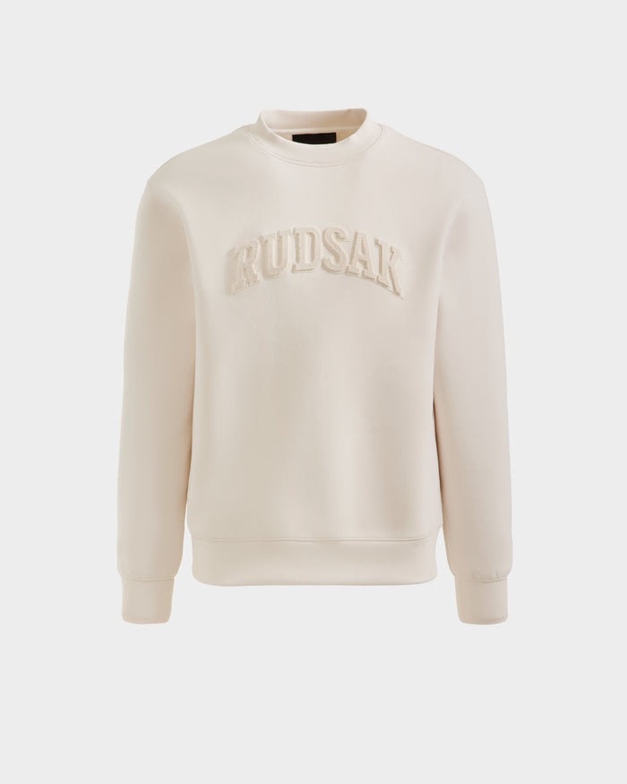 The MILOS - 6525646 Vanilla by Rudsak is a cream-colored men’s premium cotton-blend crewneck sweatshirt with long sleeves, ribbed cuffs, and RUDSAK in textured letters across the chest. Shown on a plain white background.