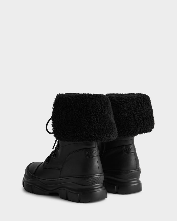 The MODENA - 8225024 Black boots by Rudsak feature chunky soles and textured faux shearling cuffs. Shown against a plain light background, the black leather winter boots are displayed with their backs facing the viewer.