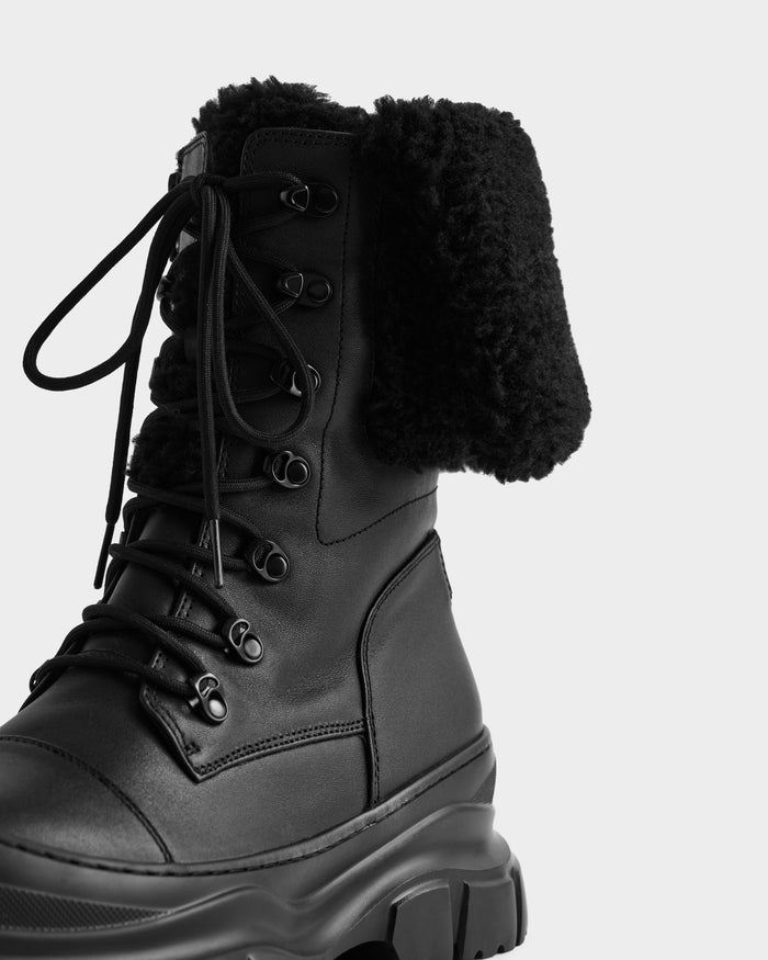 A close-up of the Rudsak MODENA - 8225024 Black boot, featuring a chunky sole and fold-over faux shearling-lined top—ideal for stylish winter wear.