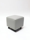 Belava Nail Tech Stool - Shorty: square gray ottoman with wheels on white background.