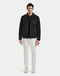 A man faces forward wearing the Rudsak NICHOLAS - 6125040 Black RDS-certified down quilted shirt jacket over a black shirt, white pants, and white sneakers against a plain light gray background.