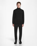 A person with light skin and brown hair stands facing forward against a white background, wearing the Rudsak NICOLAS - 6524528 Black turtleneck sweater, black dress pants, and black shoes.