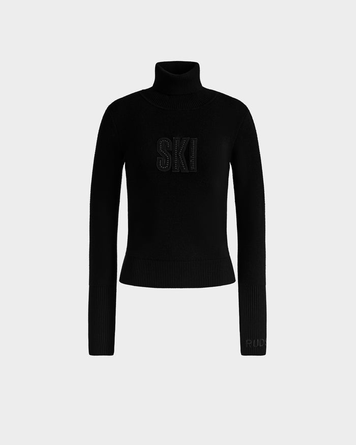 The Rudsak NOVIE - 8525659 Black women’s knit turtleneck sweater features bold SKI lettering on the chest and ribbed cuffs and hem, shown on a plain light gray background.