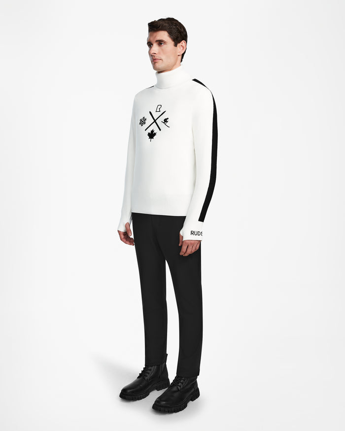 A man stands against a white background wearing the Rudsak OLIVIER - 6524545 Optic White mens ski turtleneck sweater with black graphic symbols, RUDE text, and a bold black stripe—perfect for winter wardrobes or après-ski style.
