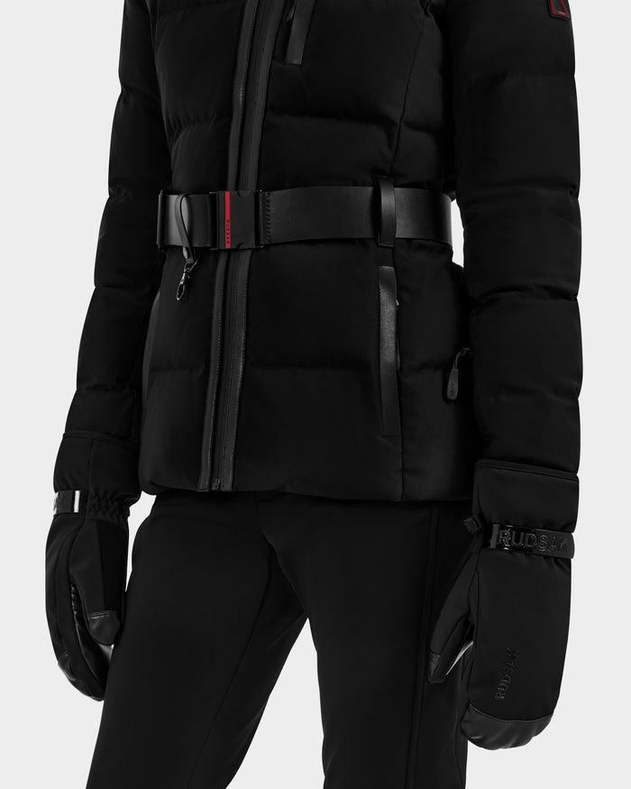 A person wearing Rudsak's OLTEN - 9425565 Black padded jacket with front zipper, black belt with a small red accent, paired with Rudsak black winter gloves featuring logo on the wrist and black pants.
