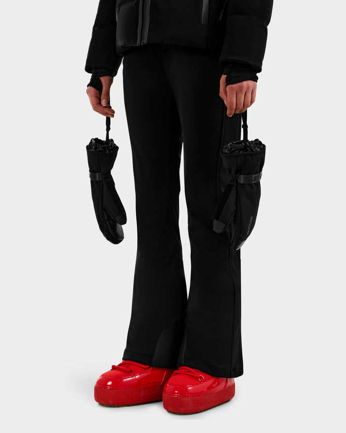 A person wearing Rudsak's OLTEN - 9425565 Black pants and jacket holds 3M Thinsulate ski mittens, paired with bright red chunky boots, standing against a plain white background.
