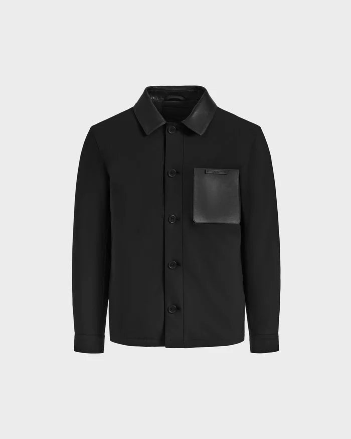 The Rudsak PALMER - 6125002 Black is a modern mens shirt jacket with a collared neck, black button-up front, and a single leather-look left chest pocket, styled as versatile outerwear against a plain light gray background.