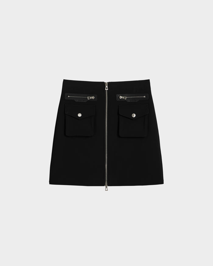 The PAMINA - 8525025 Black mini skirt by Rudsak is crafted from sleek vegan leather, with a front zipper and two zippered utility pockets with flap and button closures, shown against a plain light gray background.