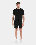 A man stands facing forward, wearing a black PASCAL - 6524022 t-shirt by Rudsak, men’s double jersey shorts with a stretch comfort waistband, and white sneakers against a plain white background.