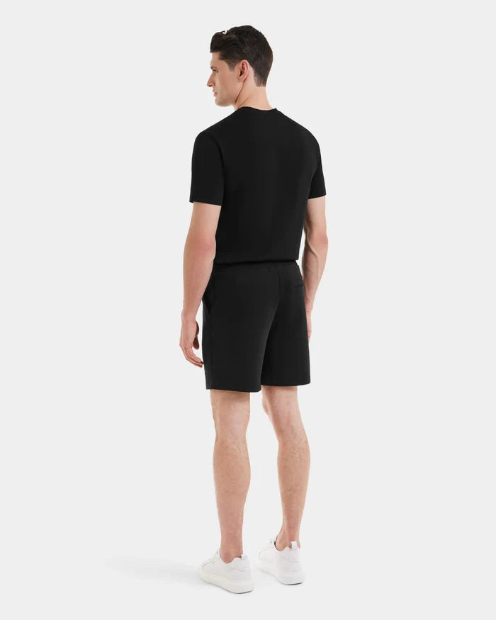 A man stands facing away, wearing a black PASCAL - 6524022 T-shirt by Rudsak and mens double jersey shorts with a stretch waistband, paired with white sneakers, against a plain light background.