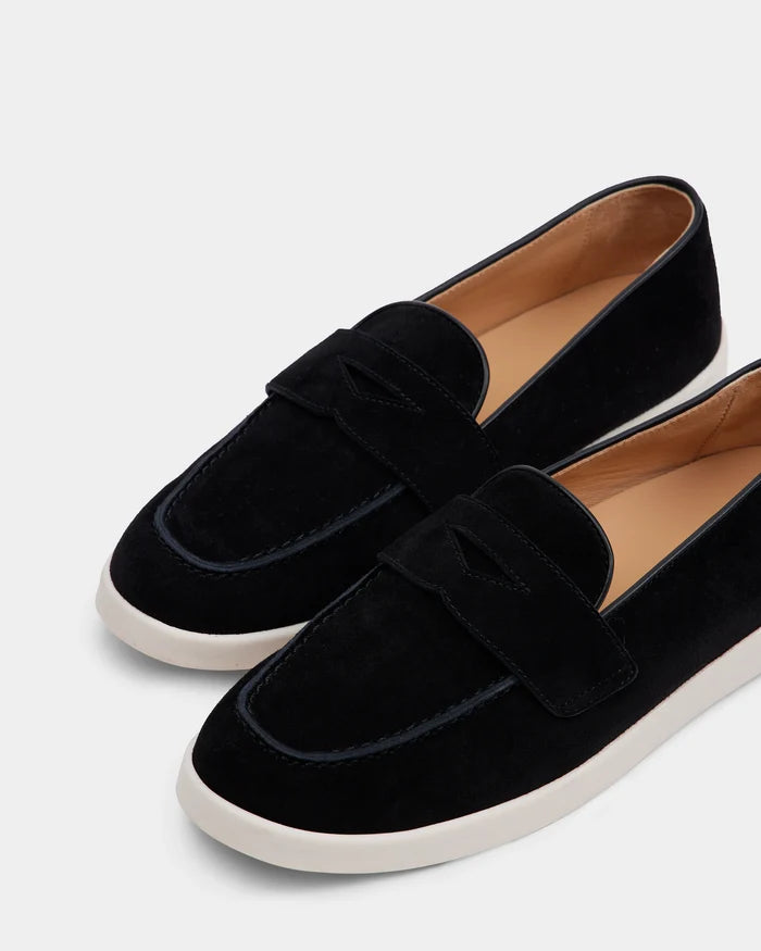 The RABECCA - 8225006 Black by Rudsak is a chic womens luxury loafer in black suede with white rubber soles and tan leather interiors, shown angled against a light gray background.