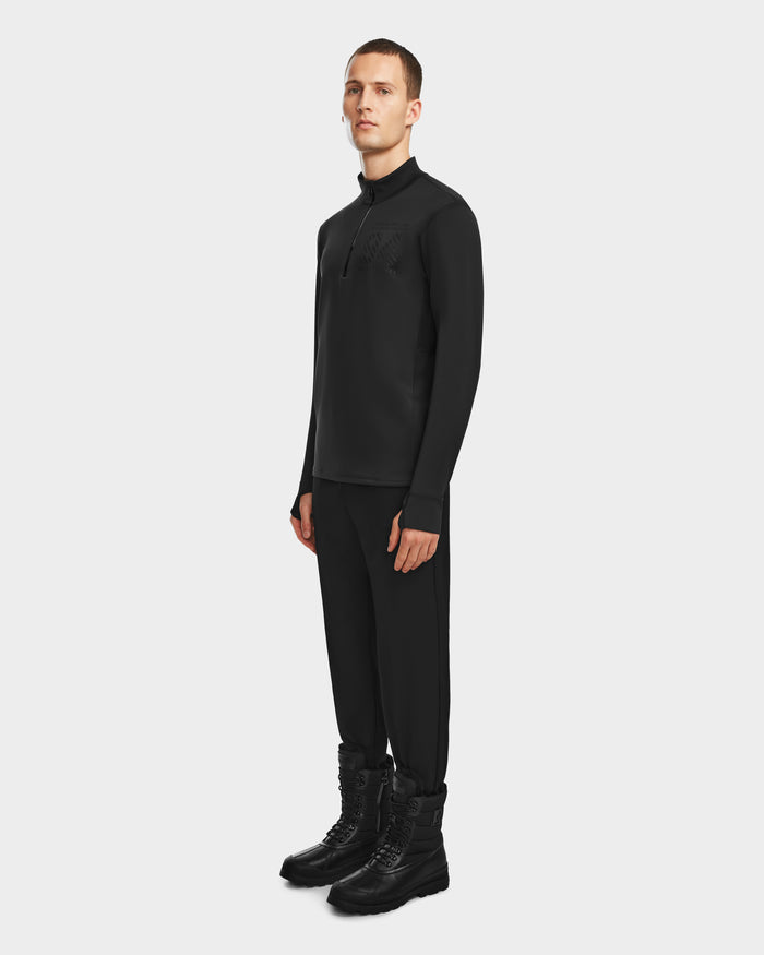A person stands against a plain white background, wearing Rudsaks RALI - 6524522 Black men’s active top. Styled all in black, they face slightly to the side with a neutral expression—ideal for winter sports or casual wear.