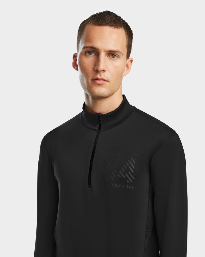 A man with short brown hair wears the Rudsak RALI - 6524522 Black men’s active top, featuring a subtle chest logo and perfect for ski layering, as he stands against a plain white background.