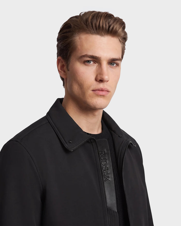 A young man with short, styled brown hair wears the Rudsak REECE - 6124592 Black men's bomber jacket with a shearling collar over a black sweater, looking at the camera with a neutral expression against a plain light background.