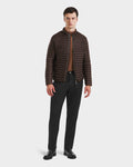A man faces forward with a neutral expression, wearing the Rudsak REYMOND M - M125523 Mocha men’s down jacket over a brown shirt, black pants, and black shoes against a plain background. The jacket is made from recycled nylon.