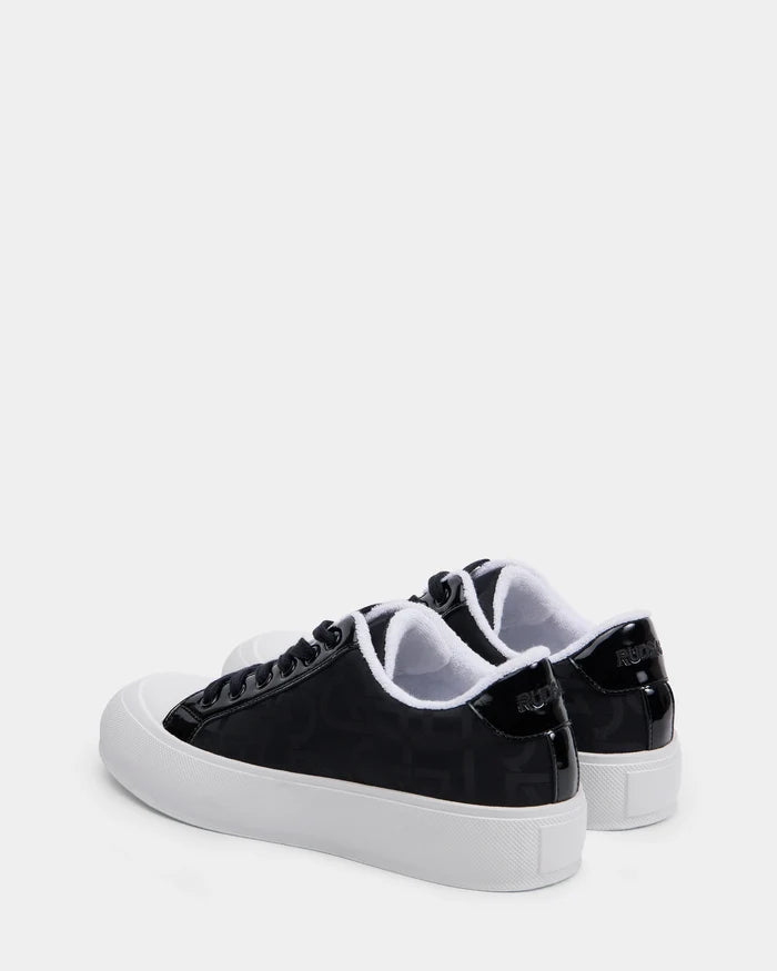 The RIMA - 8225001 Black Pattern by Rudsak are black vegan leather sneakers with white soles and toe caps, subtle monogram print on the sides, and Rudsak branding on the back heels, displayed on a plain white background.