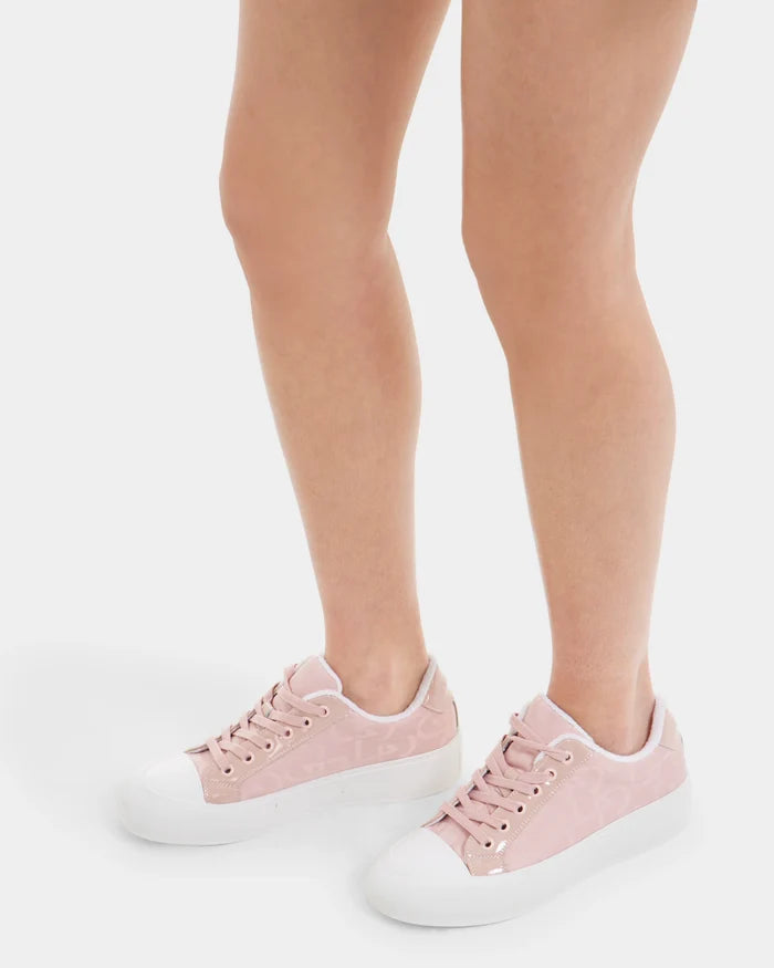 A person stands on a white surface wearing Rudsak RIMA - 8225001 Blush Pattern women’s platform sneakers with white soles and toes; only the lower legs and feet are visible.