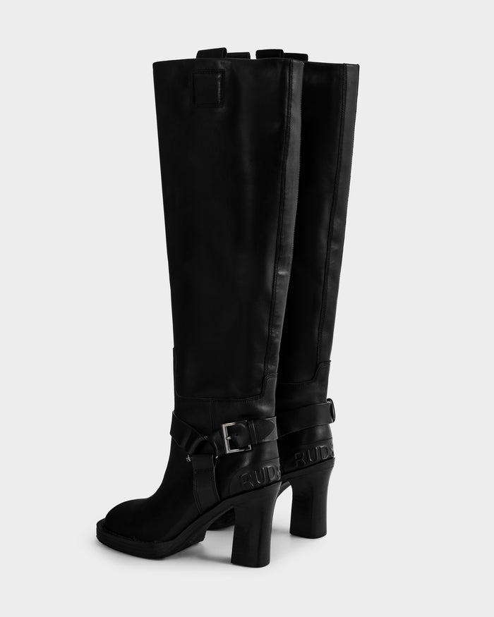 The ROSSEY - 8225574 Black boots by Rudsak are black knee-high heeled boots featuring buckles, ankle straps, and embossed side detailing, displayed against a plain light background.