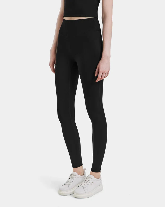 Wearing Rudsaks SONOMA - 8525071 Black high-waisted leggings, a black crop top, and white sneakers, a person stands against a light background. This sleek, modern activewear look keeps the face out of view.
