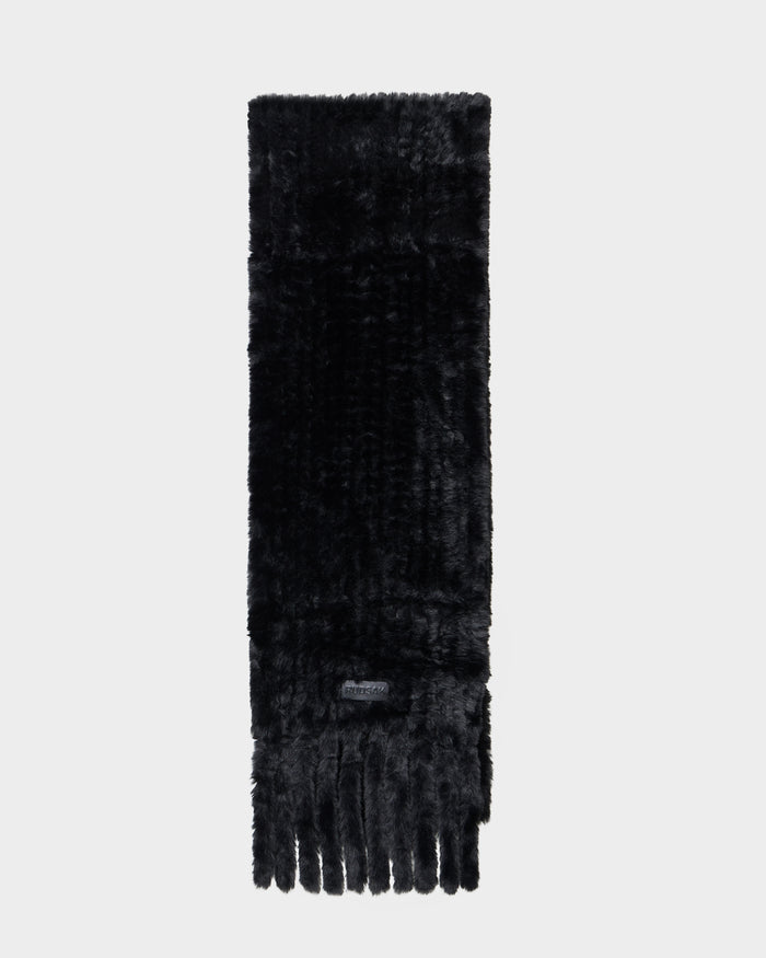 The TAVIA - 8426511 Black faux fur scarf by Rudsak features long, black fibers and fringe detailing at the ends, shown against a plain light gray background.