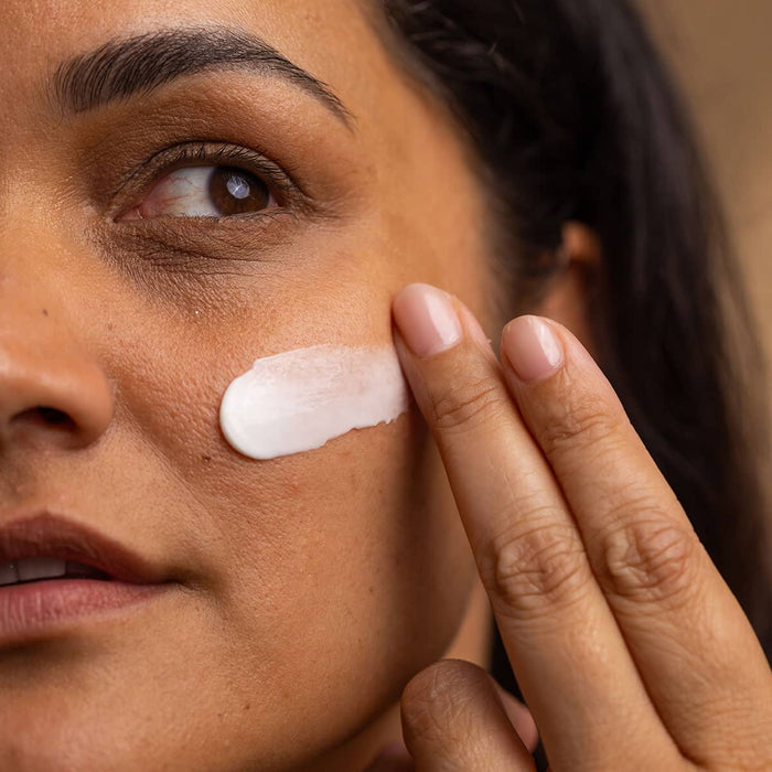 Woman applying cream to her face with a close-up view.