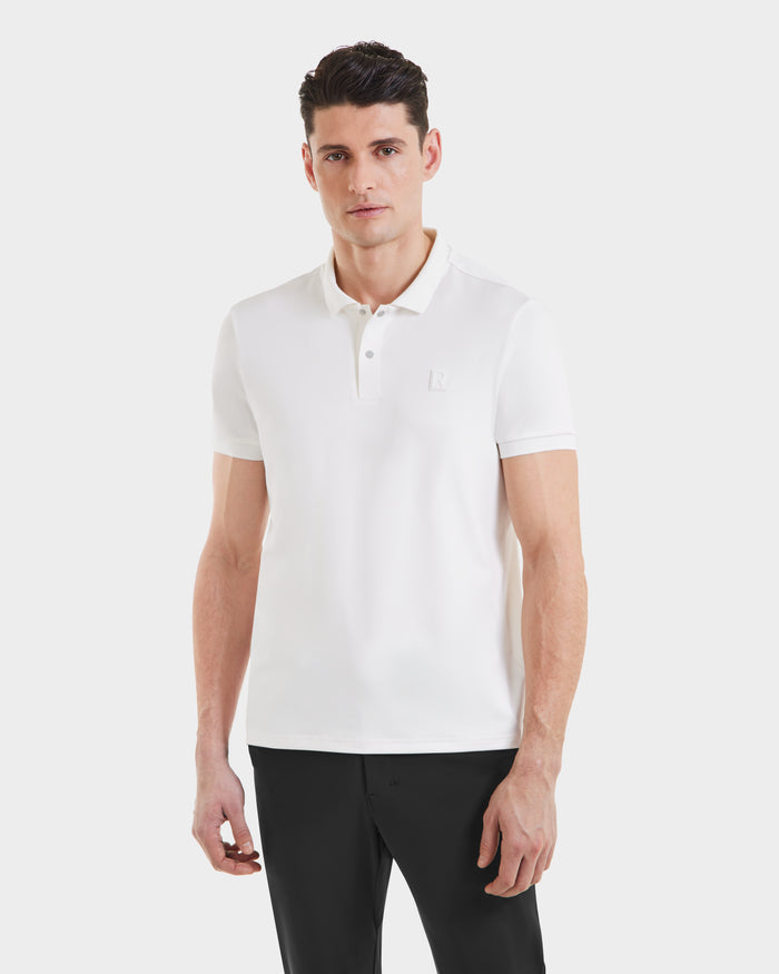 A man wears the Rudsak VICK - M523004 Optic White tailored-fit mens polo shirt with black pants, standing against a plain white background and looking at the camera with a neutral expression.